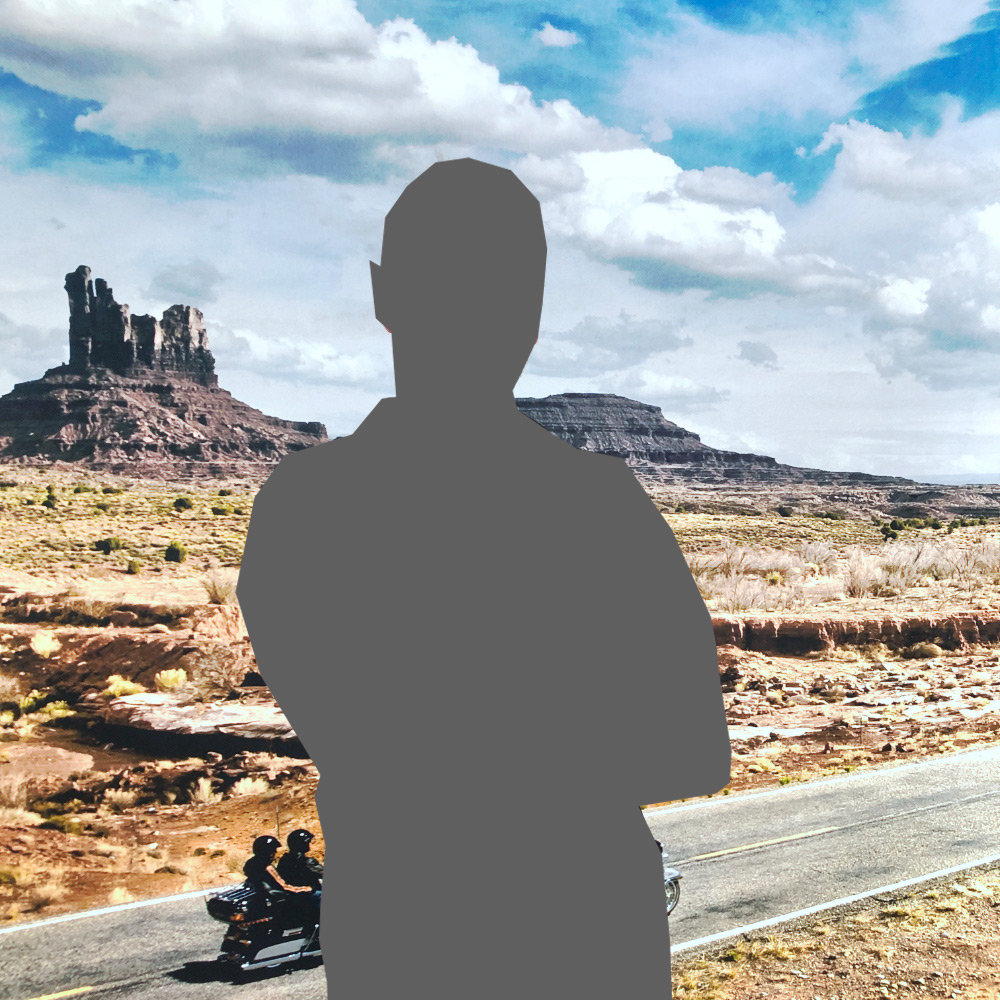 Motorradfahrer genießen die Freiheit auf einer Harley-Davidson vor einer beeindruckenden Landschaft mit Felsen und wolkenverziertem Himmel.